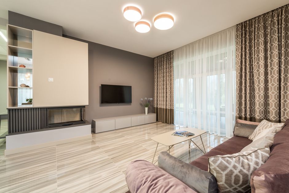 Interior of modern flat with spacious lounge and sofa with pillows under luminous lamps